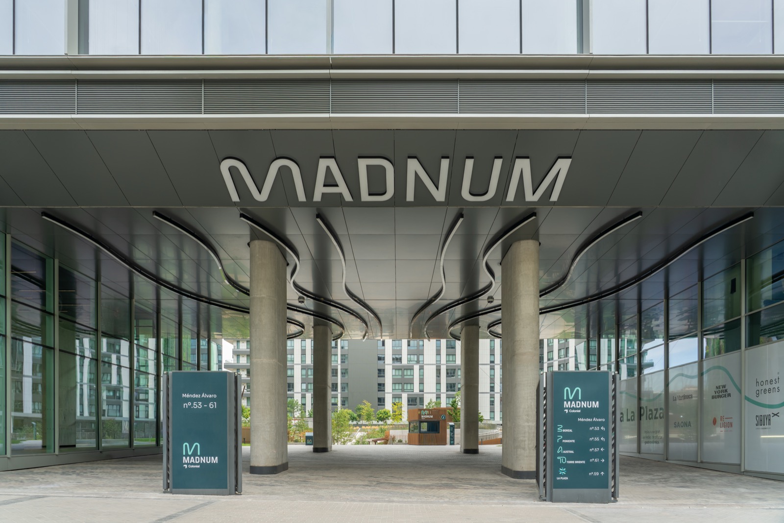 Acceso principal de Madnum, con cartelería de orientación hacia los edificios y La Plaza